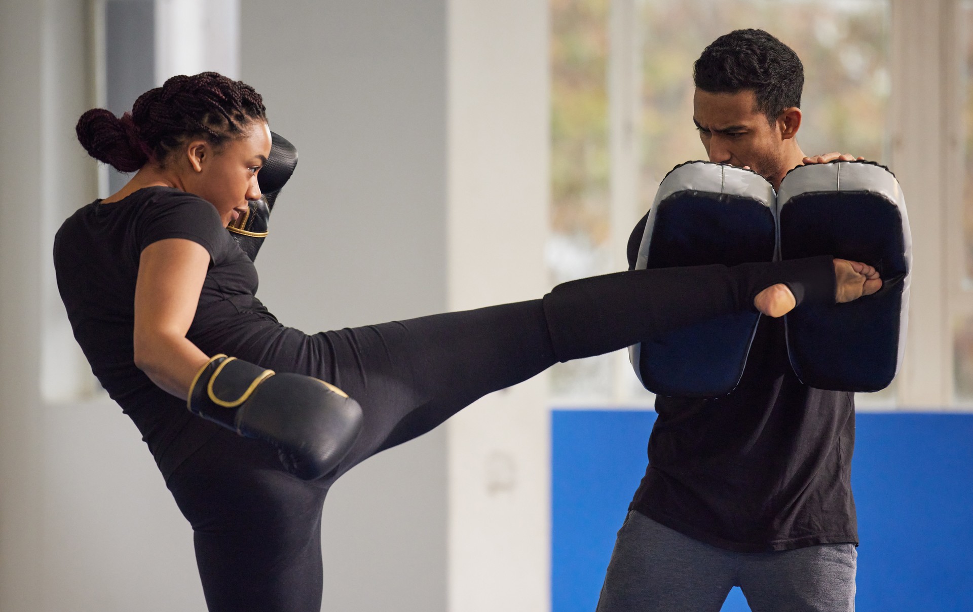 Shot of a young woman practicing kickboxing with her trainer in a gym